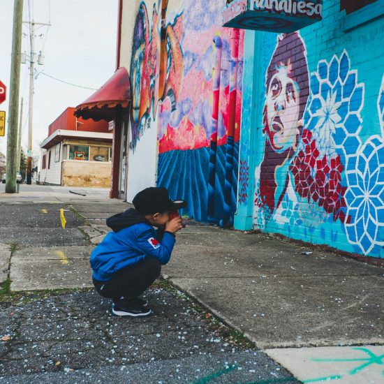 boy wearing blue hoodie in front of wall with artworks